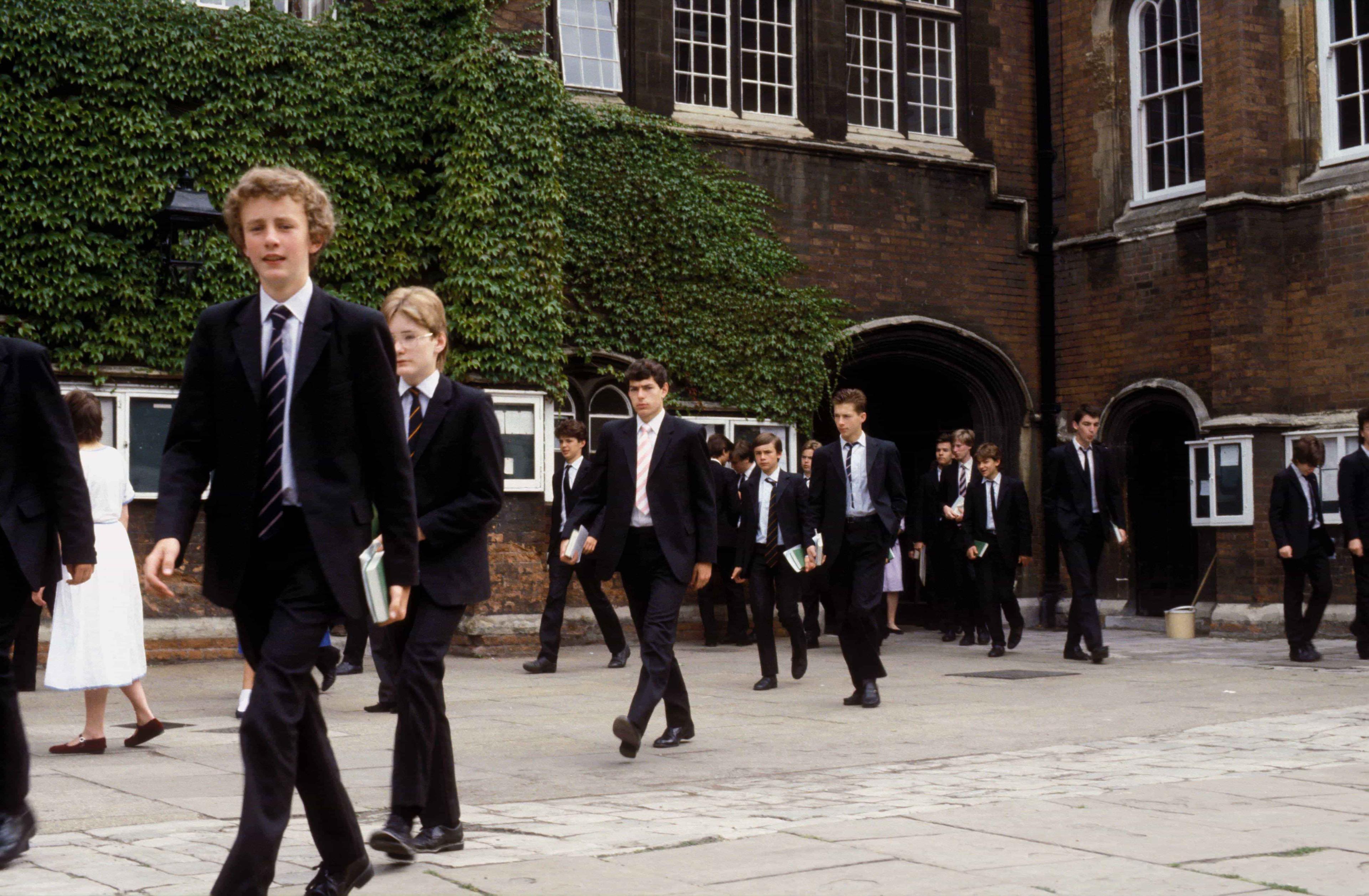 A group of A level and IB students dressed in school uniform walk around the school to their next lessons.